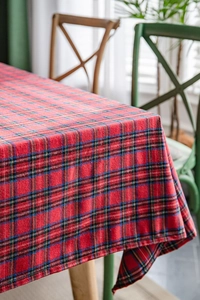 Detail of red Scottish tartan tablecloth with black stripes on a wooden dining table