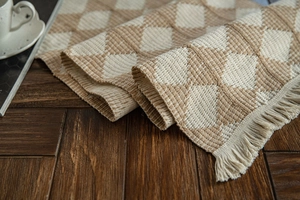 Detail of woven table runner featuring beige and brown checkerboard texture and tassels
