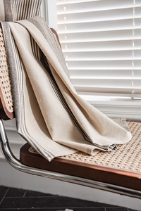 Detail of striped linen-cotton cafe curtain showing refined stitching on a wooden chair