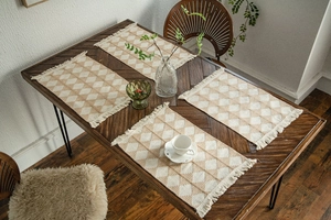 Detail of woven table mat with geometric diamond patterns and delicate fringe tassels