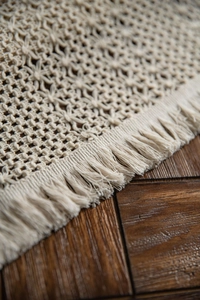 Detailed macro view of woven cream table runner with bohemian hollow pattern and tassels
