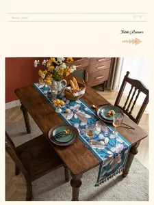 Dettaglio di runner da tavola retrò con motivi floreali tropicali e nappe colorate su legno
