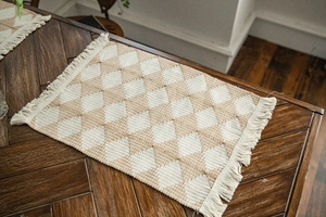 Macro detail of diamond pattern cotton weave table runner with decorative tassels