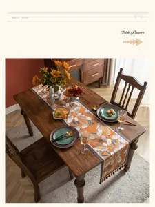 Dettaglio del runner da tavola arancione vintage con motivi floreali e nappe marroni