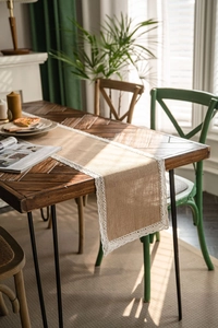 Close-up of natural jute table runner featuring delicate white lace trim on wooden desk