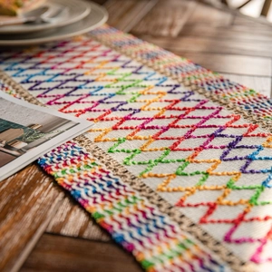Colorful embroidered table runner with geometric patterns and tassels on wooden desk
