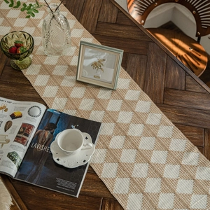 Cotton woven table runner with beige diamond patterns and tassels on dark wood table