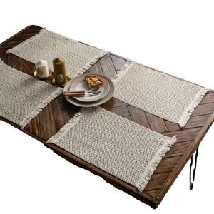Set di tovagliette bohémien intrecciate con nappe e texture a nido d'ape su tavolo
