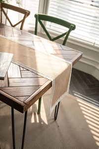 Detail of natural burlap table runner with elegant white lace borders on a wooden table
