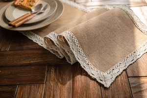 Detailed macro view of natural jute fabric texture with white lace trim on a wood table