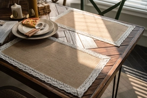 Close-up of vintage natural jute table runner with delicate white lace border details