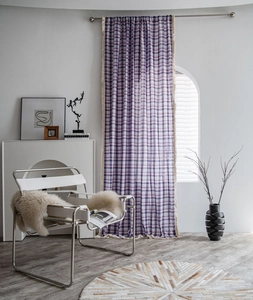 Detail of purple and white plaid curtain featuring cream tassel fringe in a cozy living room