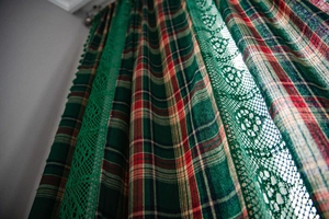 Detailed texture of green plaid curtain featuring exquisite wide lace floral trim