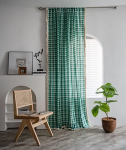 Close-up detail of green plaid curtain fabric featuring elegant beige tassel fringe trim