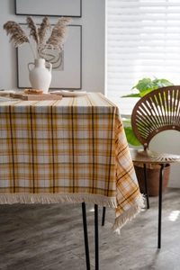 Close-up of yellow plaid tablecloth featuring detailed woven texture and white fringe tassels