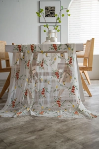 Detailopname van wit mesh tafelkleed met fijn rood geborduurde bloemen en blaadjes