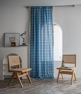 Close-up of blue and white checkered curtains with beige handmade tassels and fabric texture