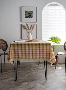 Detail of yellow and white checkered tablecloth featuring elegant cream fringe tassels