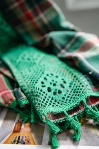Detail of green crochet hollow floral pattern with decorative fringe tassels