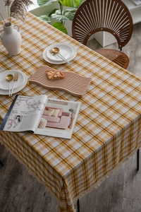 Detailed view of yellow and white plaid tablecloth with delicate white fringe tassels on edges