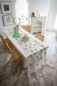 Detail van een witte kanten tafelloper met verfijnd kleurrijk geborduurde bloemen