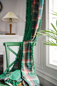 Detail of green plaid curtain with intricate lace trim and fringe in a cozy vintage room