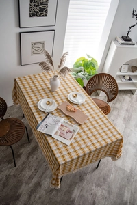 Detail of yellow and white checkered tablecloth with decorative off-white tassel fringe