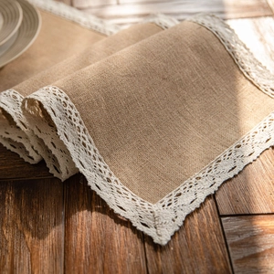 Natural jute table runner with white floral lace trim on dark wood tabletop