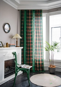 Detail of green plaid curtain with delicate lace trim and matching tassels in a cozy room