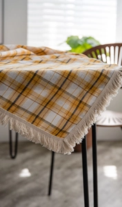Detailed view of yellow and blue checkered tablecloth with delicate beige tassel edges