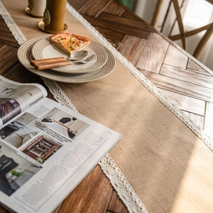 Natural jute table runner with white lace edges on a dark wooden dining table