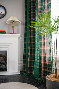 Detail of green plaid curtain with intricate lace trim and decorative fringe tassels