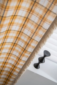 Close-up of yellow plaid fabric with soft fringe details for window curtains