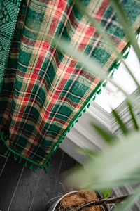 Detail of green plaid curtains with classic fringe edges and textured cotton fabric