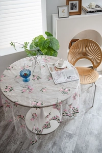 Close-up of pink flower embroidery and wavy lace edge on white mesh tablecloth