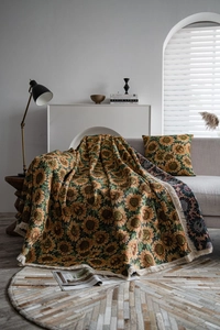 Detail of sunflower jacquard knit throw blanket with tassels on a gray sofa