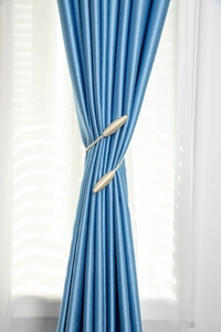 Détail d'embrasse de rideau torsadée avec boucle métallique spirale couleur champagne