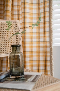 Detail view of yellow plaid curtains with elegant beige tassels and linen texture