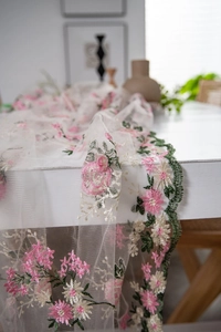 Detail of pink and white flower embroidery on white mesh lace fabric for table decoration