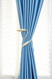 Détail de l'embrasse de rideau en spirale dorée sur un tissu élégant en satin bleu