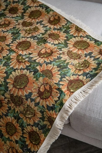 Close-up of jacquard woven sunflower pattern and white fringe tassels on sofa throw