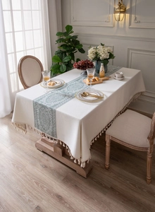 Detail of elegant beige table cloth with green damascus pattern and fringe tassels
