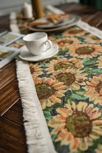 Detailed close-up of woven sunflower jacquard table runner with cotton tassel edge