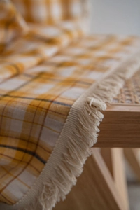Detail of yellow and white plaid textile with elegant off-white tassel fringe trim