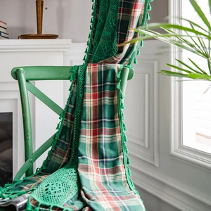 Green and red plaid curtain with crochet lace trim and tassels draped over a vintage chair