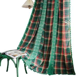 Green and red plaid curtain with floral lace edge and pompom tassels in farmhouse style