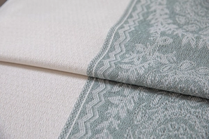 Macro shot of cream and sage green woven fabric with intricate floral jacquard pattern