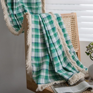 Green and white plaid checkered curtain with fringe tassel hanging on a wooden chair