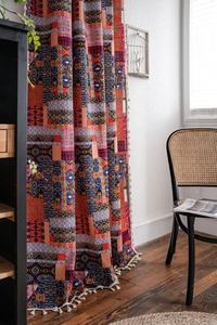 Detail of bohemian printed curtain with multi-color patterns and white tassel fringe