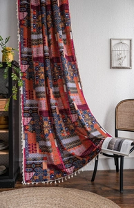Detail of Bohemian printed curtain with vibrant ethnic patterns and white tassel trim